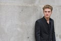 Attractive blue eyed, blond young man leaning with his back against wall Royalty Free Stock Photo