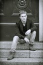 Attractive blue eyed, blond young man sitting on stair steps Royalty Free Stock Photo