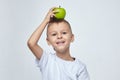 Attractive boy holds a green Apple on his head. photo session in the Studio on a white background Royalty Free Stock Photo