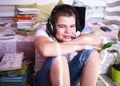 Attractive boy pensive, dreamy in a white t-shirt and jeans, in headphones is studying with a books and a laptop. Distance Royalty Free Stock Photo