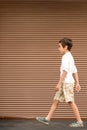 The attractive boy wearing white shirt stands at a brown rolling