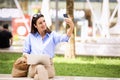 Attractive brown-haired woman is sitting on a bench in the street using a laptop and mobile phone Royalty Free Stock Photo