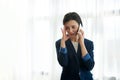 Attractive brunette, female employee, business woman putting hand on her temple while having a boring conversation on the phone Royalty Free Stock Photo