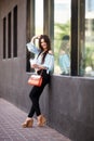 Attractive brunette girl with long hair standing near cafe. She wears Blue blouse with open shoulders Royalty Free Stock Photo