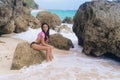 Attractive brunette girl in swimsuit posing and sunbathing on rocky beach Royalty Free Stock Photo