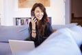 Cheerful attractive woman using mobile phone and laptop while relaxing at home Royalty Free Stock Photo