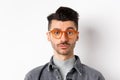 Attractive brunette man with moustache, wearing stylish glasses and look serious at camera, no emotion pokerface