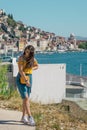 Attractive brunette wearing a blue skirt and an orange top posing outside near the sea on a warm summer day. Long hair flowing in Royalty Free Stock Photo