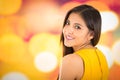 Attractive brunette wearing yellow dress posing naturally and smiling beautiful to camera with blurry colorful Royalty Free Stock Photo