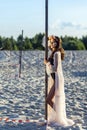 Attractive brunette woman in black body and translucent beach cover up posing on sandy beach at sunset. standing with hand on Royalty Free Stock Photo