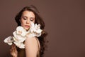 Attractive brunette woman fashion model with white beautiful flowers. Beautiful female model with long healthy brown hair on brown Royalty Free Stock Photo