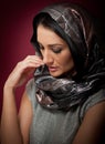 Attractive brunette woman in gray blouse and headscarf posing dramatic on purple background. Female art portrait, studio shot Royalty Free Stock Photo