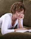 Attractive brunette woman relaxing on couch with book