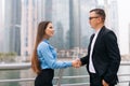 An attractive business man and woman team shaking hands outdoors on skyscrapers Royalty Free Stock Photo