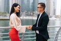 An attractive business man and woman team shaking hands outdoors on skyscrapers Royalty Free Stock Photo