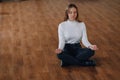 Attractive business-style girl sits on the floor in a lotus position. yoga in the office, relaxation at work. search for harmony