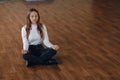 Attractive business-style girl sits on the floor in a lotus position. yoga in the office, relaxation at work. search for harmony