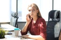 Attractive business woman talking with collegues on the mobile phone while sitting in the office desk Royalty Free Stock Photo