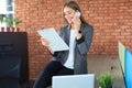 Attractive business woman talking with collegues on the mobile phone while sitting on the office desk Royalty Free Stock Photo