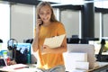 Attractive business woman talking with collegues on the mobile phone while sitting on the office desk Royalty Free Stock Photo