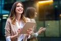 Attractive business woman using a digital tablet while standing in front of windows in an office Royalty Free Stock Photo