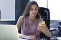 Attractive business woman using smart phone while sitting at the office desk Royalty Free Stock Photo