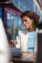 Attractive business woman in white suit sitting in cafe and using phone Royalty Free Stock Photo