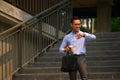 Attractive businessman in front of the building and checking time on wristwatch for appointment Royalty Free Stock Photo