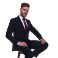 Attractive businessman in navy suit resting on wooden chair Royalty Free Stock Photo