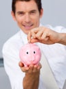 Attractive businessman saving money in a piggybank Royalty Free Stock Photo