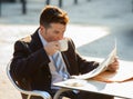 Attractive businessman sitting outdoors having coffee cup for breakfast early morning reading newspaper news looking relaxed Royalty Free Stock Photo