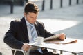 Attractive businessman sitting outdoors having coffee cup for breakfast early morning reading newspaper news looking relaxed Royalty Free Stock Photo
