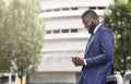 Attractive businessman texting on cellphone, standing near modern office building Royalty Free Stock Photo