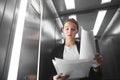 Attractive businesswoman is checking the documentation with skeptical look in the elevator. Portrait of a young female office Royalty Free Stock Photo