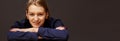 Attractive businesswoman with a confident friendly smile posing with folded arms against a dark background with copy