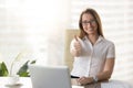 Attractive businesswoman looking at camera, showing thumbs up at Royalty Free Stock Photo