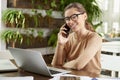 Attractive businesswoman making a call while sitting in front of laptop in the office and working Royalty Free Stock Photo