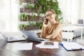 Attractive businesswoman making a call while sitting in front of laptop in the office and working Royalty Free Stock Photo