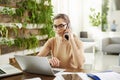 Attractive businesswoman making a call while sitting in front of laptop in the office and working Royalty Free Stock Photo