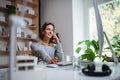 Attractive businesswoman sitting at the desk indoors in office, using smartphone. Royalty Free Stock Photo