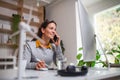 Attractive businesswoman sitting at the desk indoors in office, using smartphone. Royalty Free Stock Photo