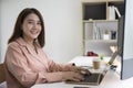 Businesswoman sitting at office desk with her laptop and smiling to camera. Royalty Free Stock Photo