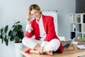 attractive businesswoman sitting on table and looking at camera