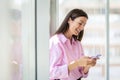 Attractive businesswoman standing at the glass office and text messaging Royalty Free Stock Photo