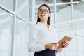 Attractive businesswoman using a digital tablet while standing in a large corporate building Royalty Free Stock Photo