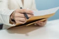 Attractive businesswoman in white suit hand open business report from document envelope and working on desk Royalty Free Stock Photo