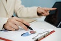 Attractive businesswoman in white suit working and calculating about finance with document report and digital mobile tablet Royalty Free Stock Photo