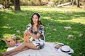 Attractive Asian woman is listening to music on her headphones and reading a book while picnicking Royalty Free Stock Photo