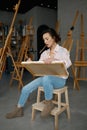 Attractive young woman artist holding canvas in hand drawing picture Royalty Free Stock Photo