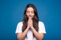 Attractive caucasian or arab brunette girl in a white t-shirt standing in a meditative pose and showing a prayer gesture isolated